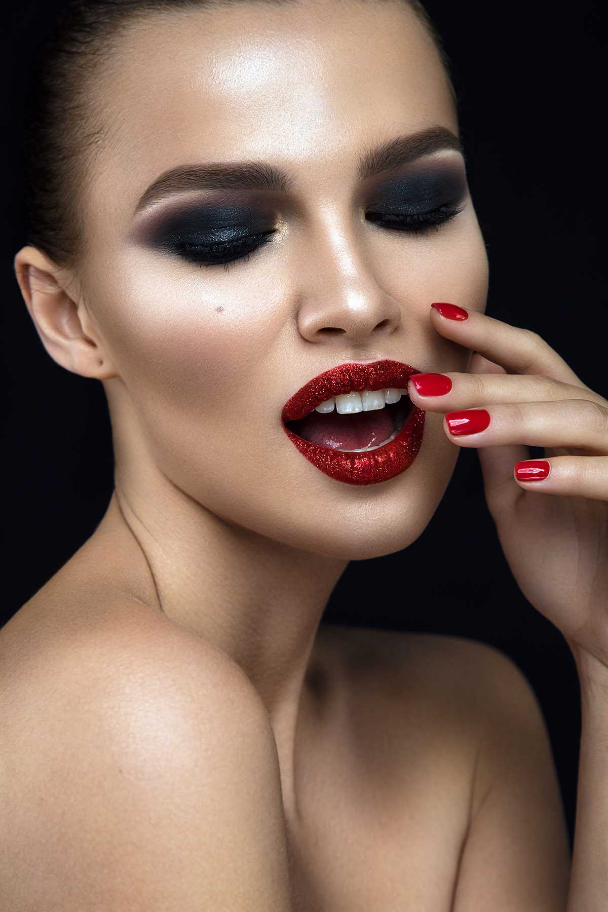 Fashion woman portrait on black background with red shiny lips.