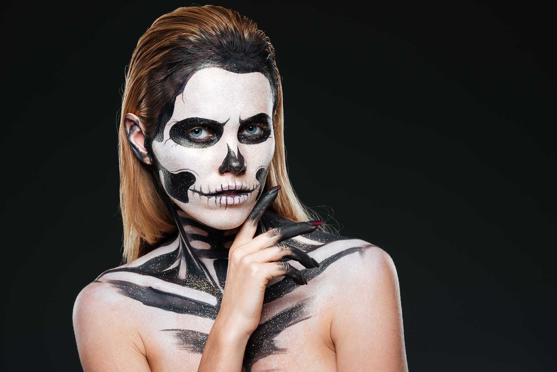 Young woman with gothic skeleton makeup over black background